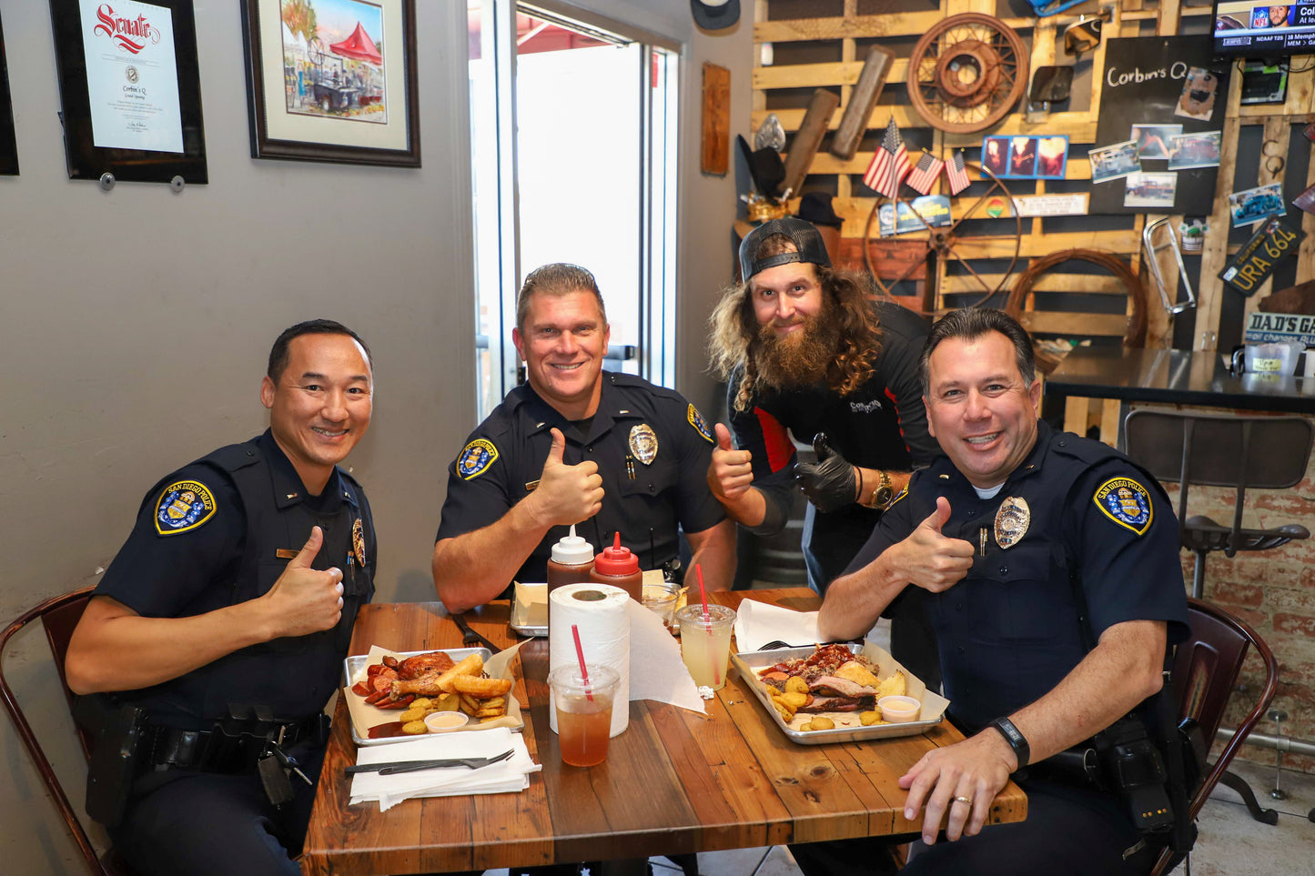 Three San Diego Police officers take a picture with Corbin's Q owner while they enjoy some barbecue from his restaurant by SDSU.