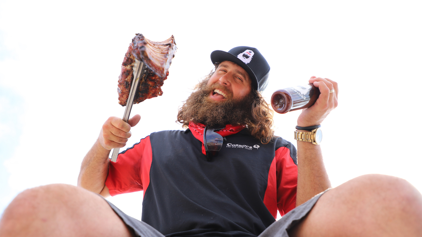 Corbin, owner of Corbin's Q Bar and Barbecue in the college area, smiles while holding up a rack of pork ribs and his sweet barbecue sauce.