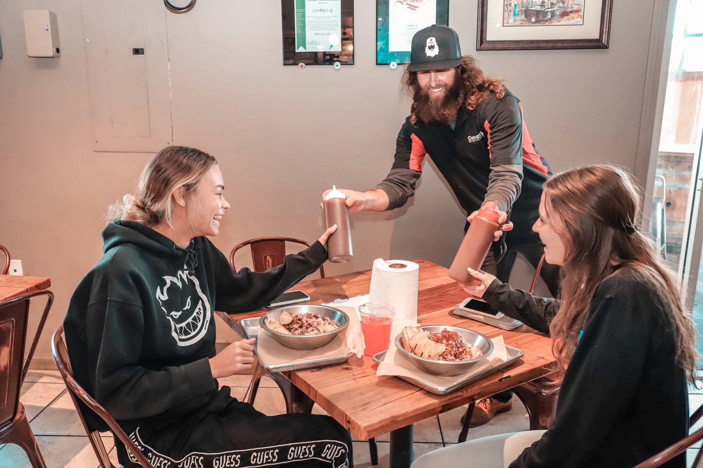 Corbin brings some sweet and some spicy barbecue sauce to two customers at they enjoy their pulled pork loaded fries. 