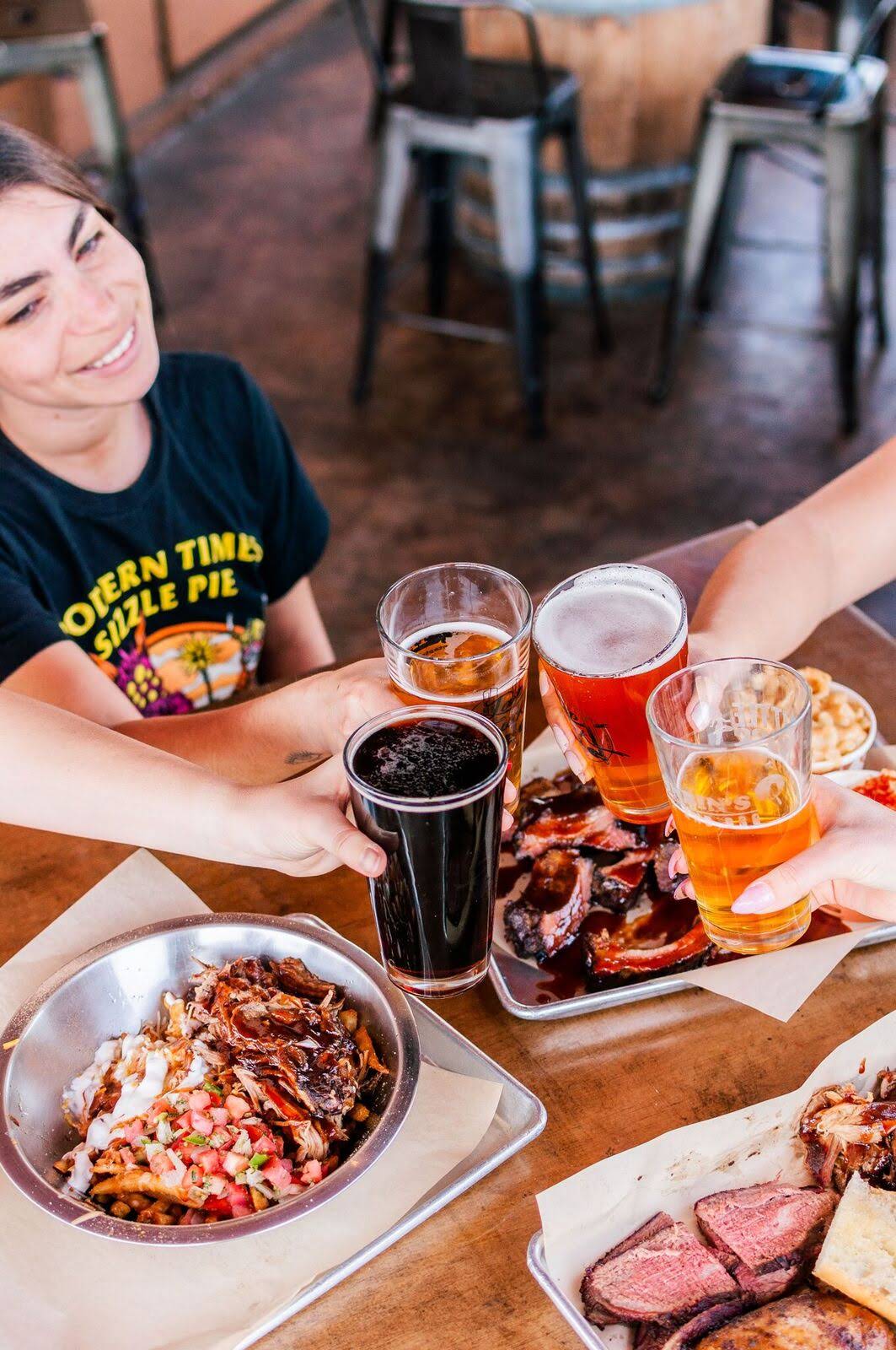 Customers move their glasses in for a cheers while they enjoy some delicious barbecue from Corbin's Q bar and barbecue. 