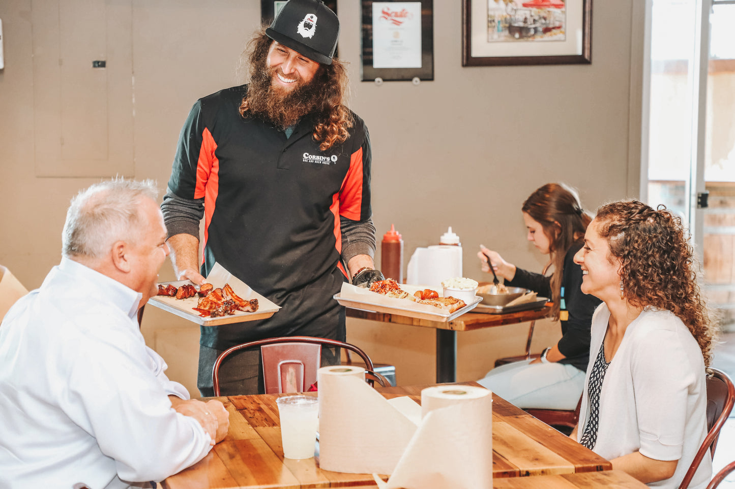 Corbin delivering Linguica Sausage, pork ribs, and pulled pork to two happy customers at his barbecue restaurant near SDSU