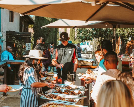 Guests serve themselves from choices of tri tip, pork ribs, and linguica sausage during an on-site catering buffet. 