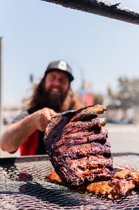 Corbin smiles as he holds up a rack of beef ribs, served every Wednesday and Saturday at Corbin's Q bar and barbecue. 