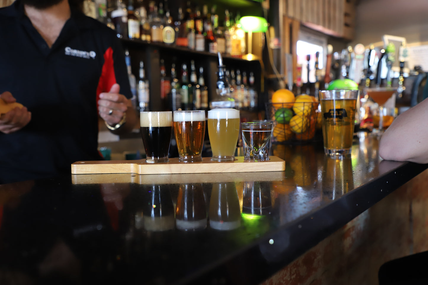 Three draft beer tasters on a paddle alongside one well shot of vodka from Corbin's Q bar and barbecue. 