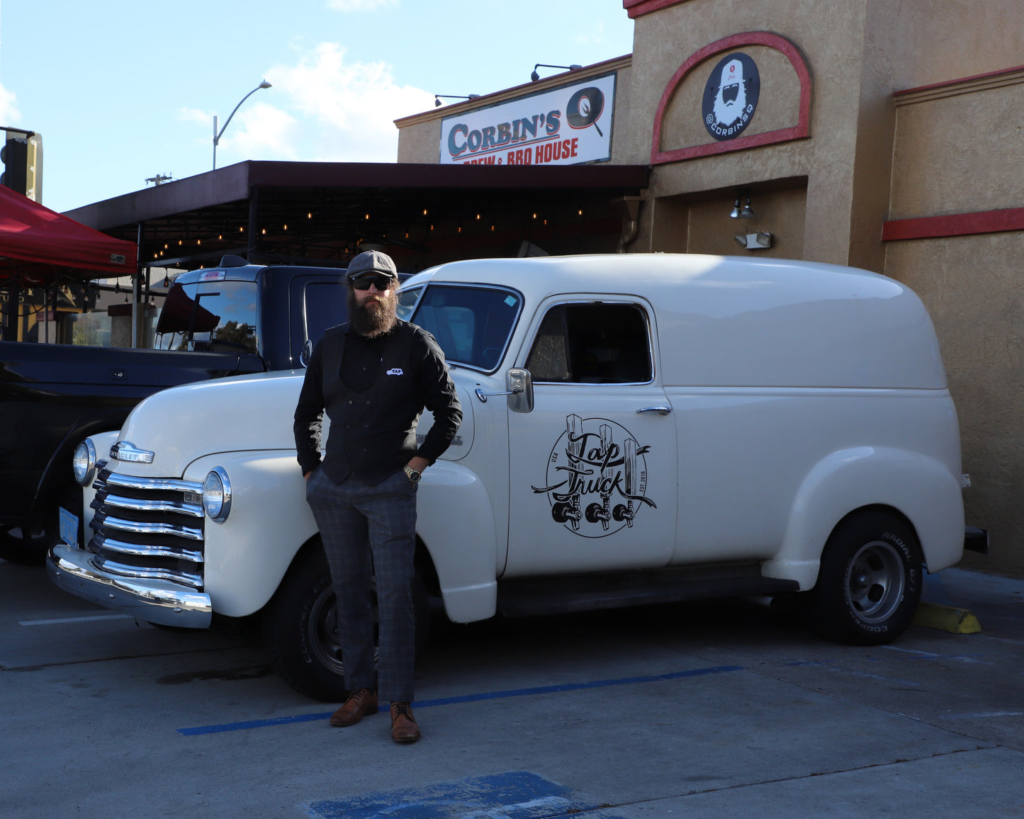 Corbin stands in front of his vintage mobile bar parked in front of his restaurant, Corbin's Q, in Rolando San Diego.  