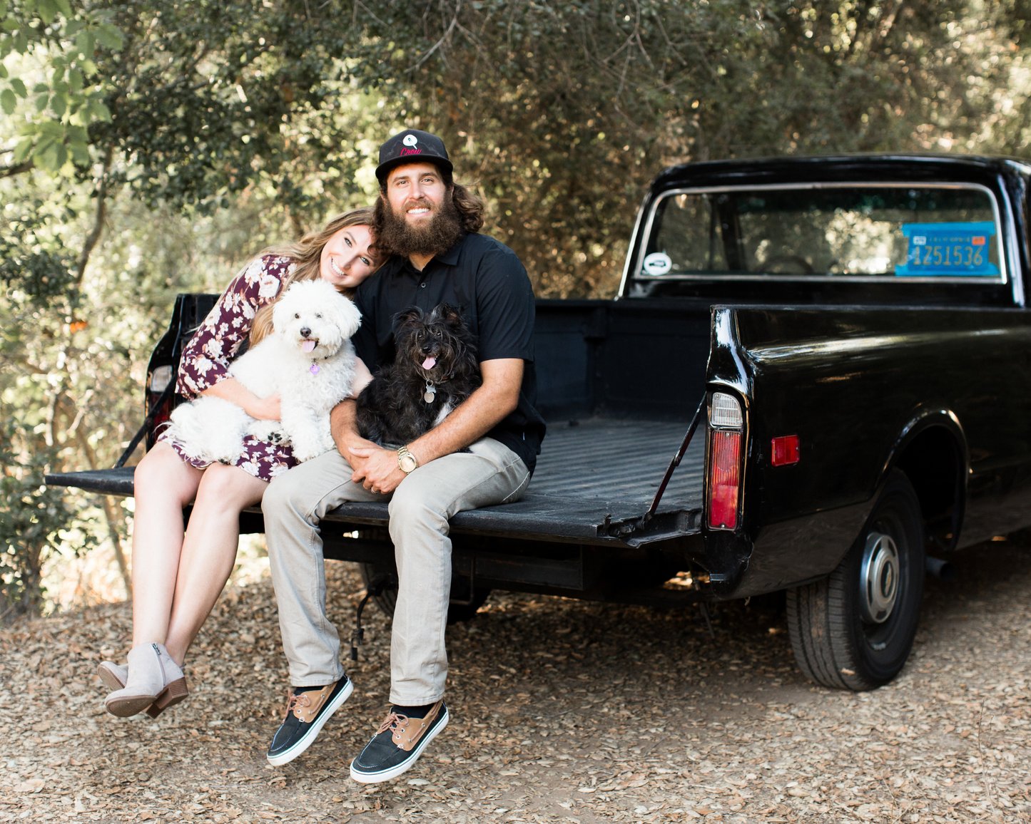 Corbin and his wife Meghan sit on the bed of their trucks with their two dogs. 