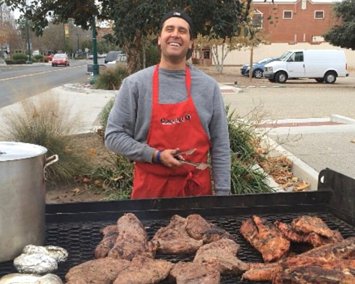 Young Corbin smiles as he grills some tri tip and pork ribs for an on-site catering event in San Diego. 